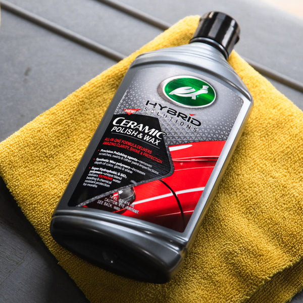 Turtle Wax Hybrid Solutions Ceramic Polish & Wax bottle on a yellow microfiber towel. Car care product for shine and paint protection.